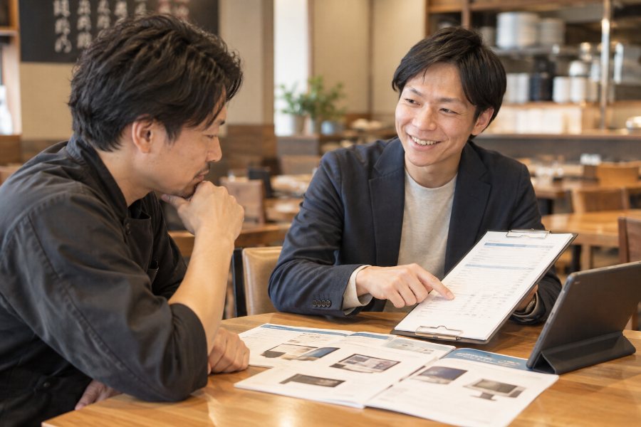 店内で見積書を指しながら店主に説明する担当者
